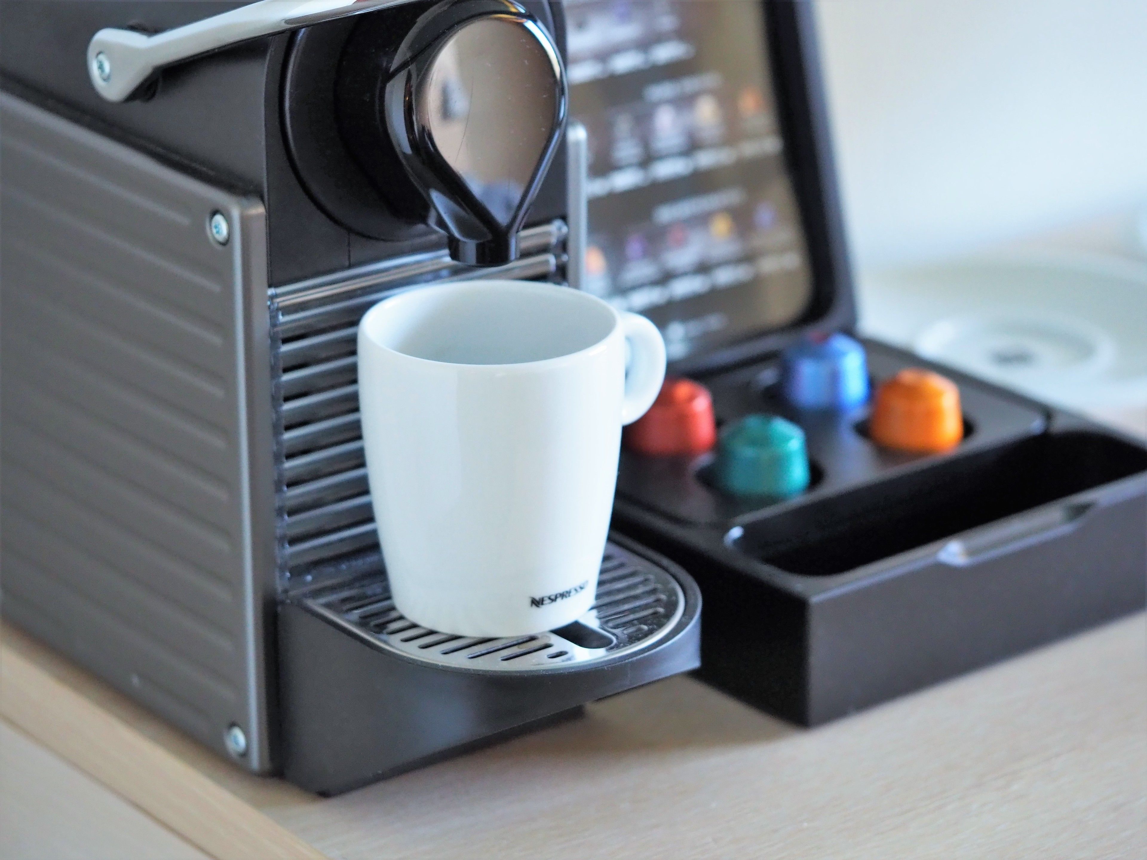 A coffee machine with a cup holder and a coffee pod compartment.