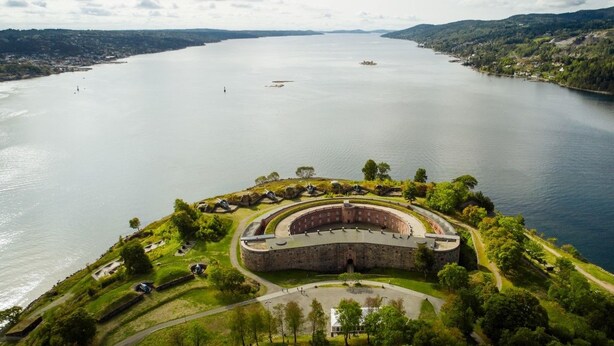 A large, circular fortress-like structure with a central courtyard, surrounded by lush greenery and a calm lake. - Oscarsborg Castle Hotel & Resort (Frogn)
