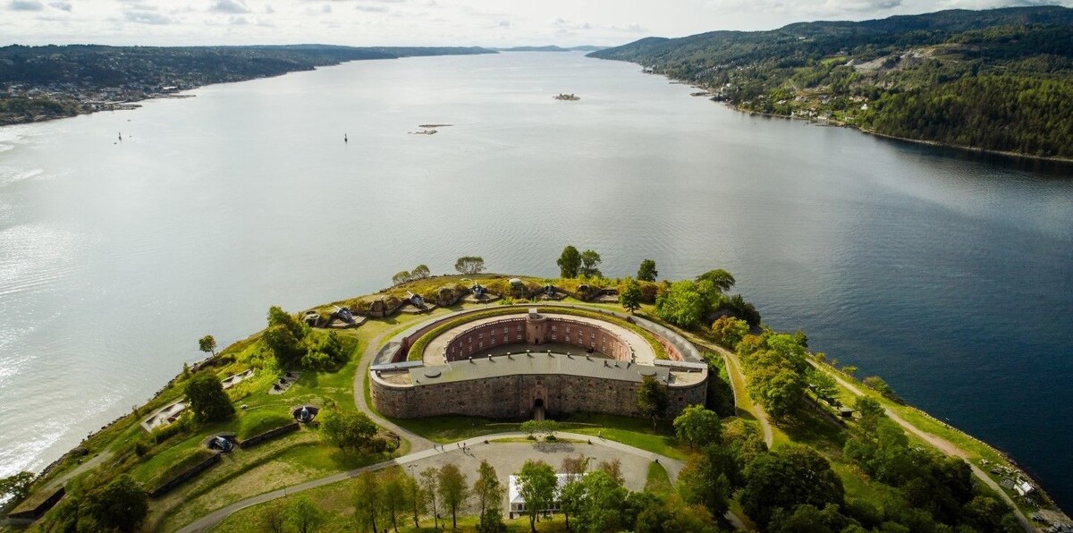 Half moon shaped castle on a green peninsula surrounded by water