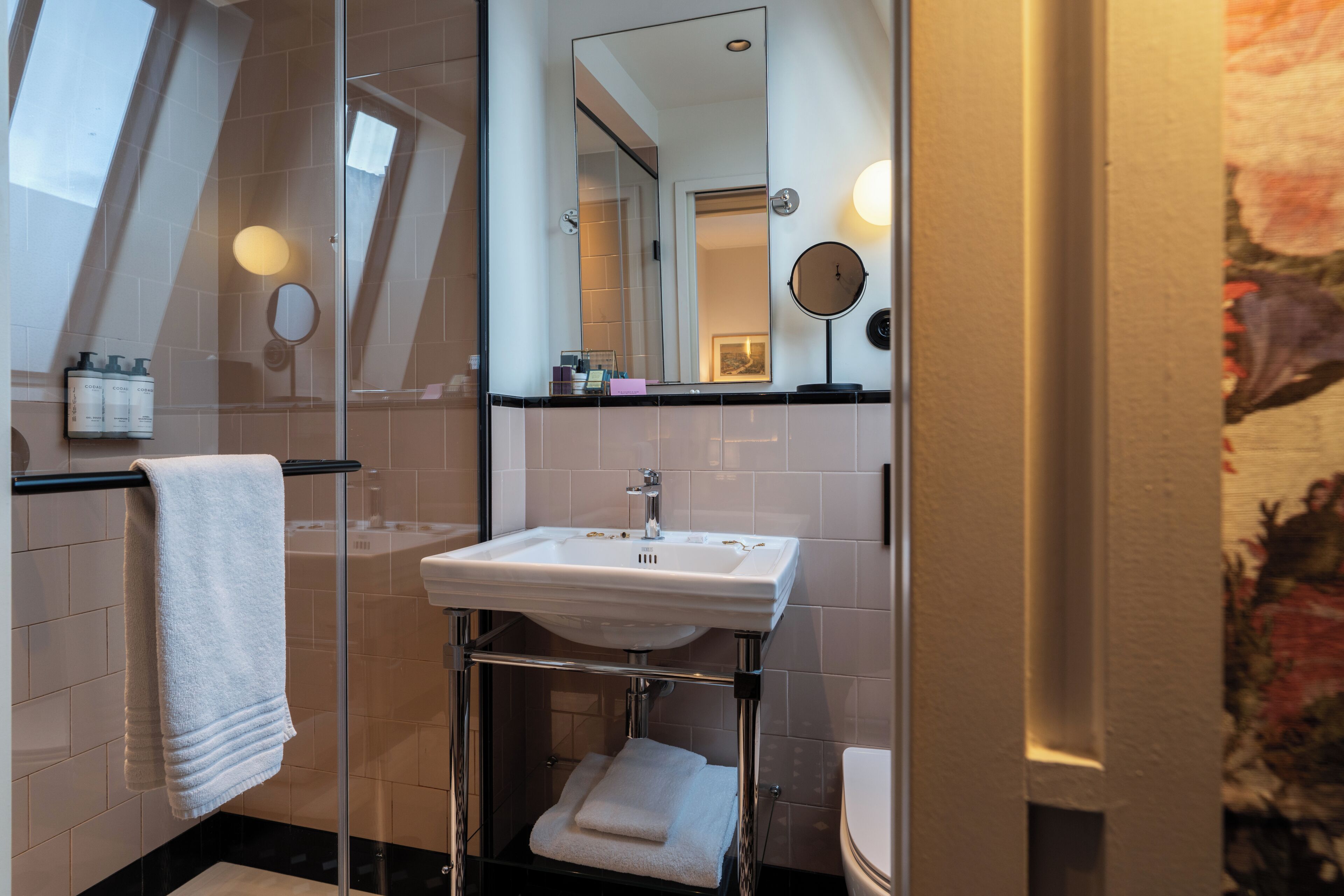 Une salle de bain avec une douche à parois de verre, un lavabo blanc et un miroir.