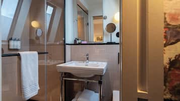 Une salle de bain avec une douche à parois de verre, un lavabo blanc et un miroir.