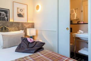 A hotel room with a bed, a bathroom with a sink and towel rack, and a framed picture on the wall.