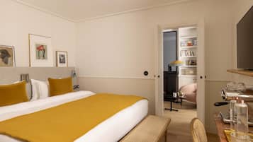 A hotel room with a large bed, a bedside table with a lamp, a chair, and a small table with a coffee maker.