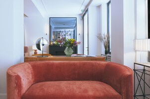 Un salon moderne avec un canapé en velours rouge, une table basse en bois et un vase rempli de fleurs.
