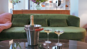 A green sofa, a metallic champagne bucket, and two wine glasses on a reflective surface. - Dadou Paris (Paris)