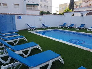 A swimming pool with blue lounge chairs arranged around it. - Hotel Comarruga Platja (El Vendrell)