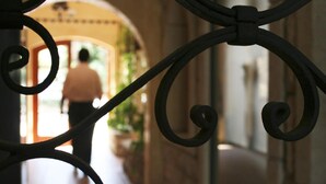 Un pasillo con una puerta de hierro forjado decorativa, que conduce a un acceso por donde una persona está caminando.