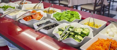 A buffet with various food items including vegetables, cheese, and eggs.