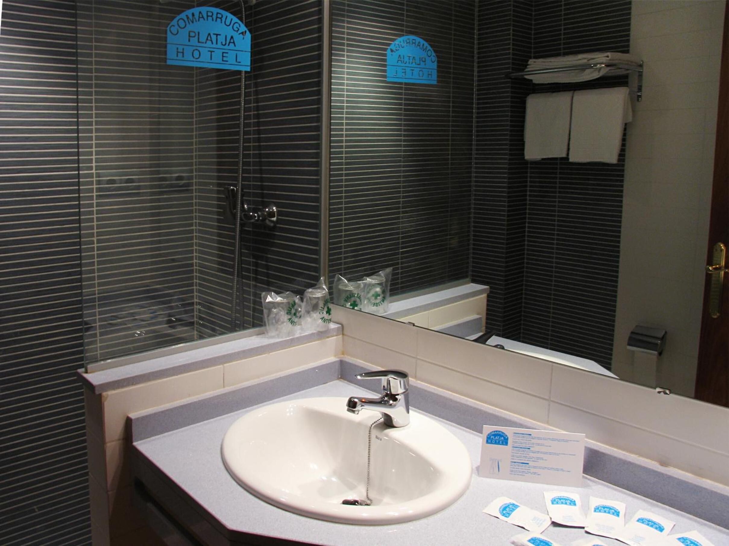 Un baño de hotel con lavamanos, espejo y ducha.