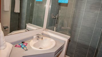 A bathroom with a sink, mirror, and towel rack. There are signs indicating the hotel name.