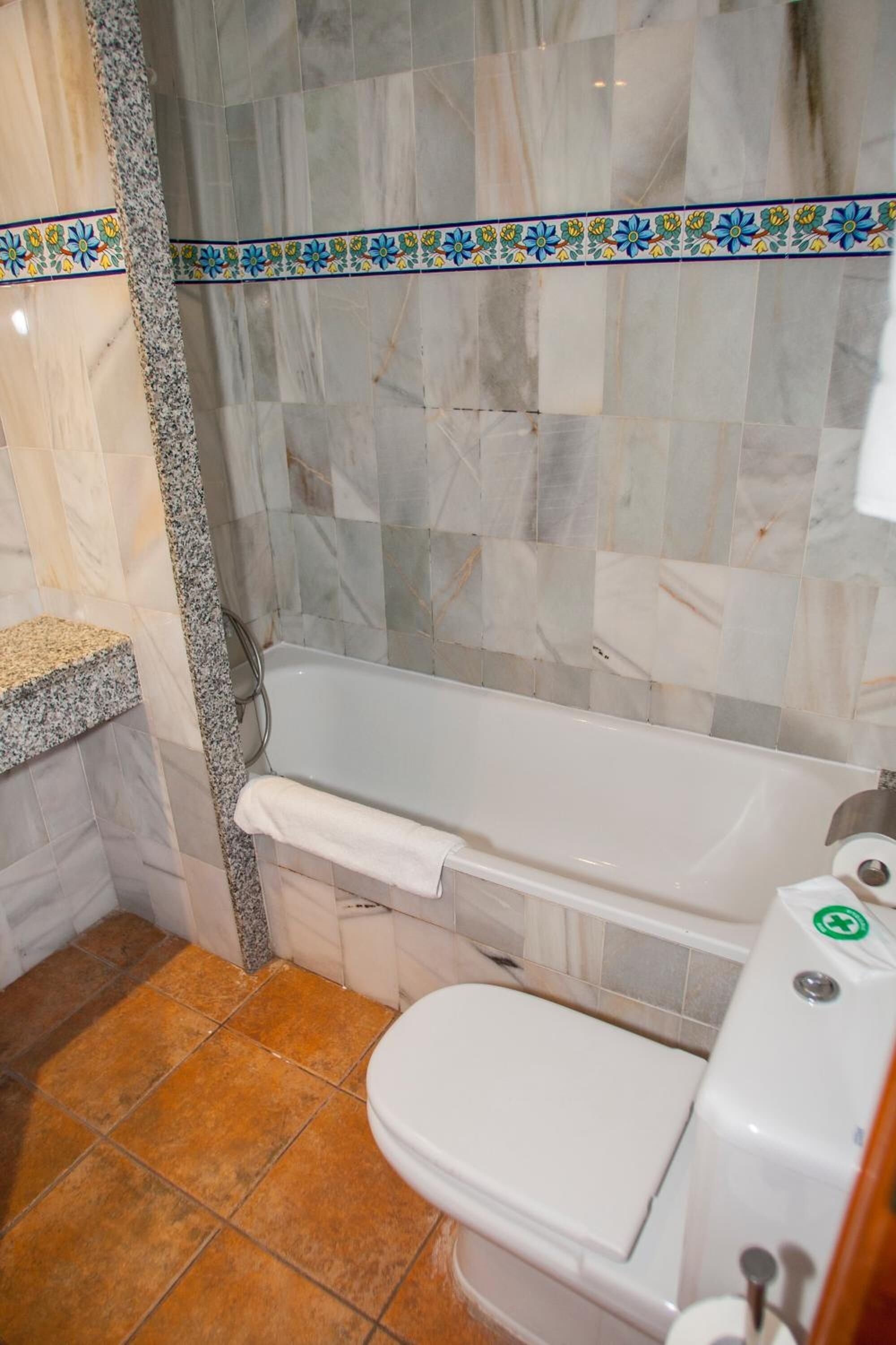 A bathroom with a bathtub, toilet, and a shower area.