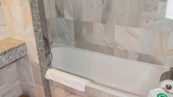 A bathroom with a bathtub, toilet, and a shower area.