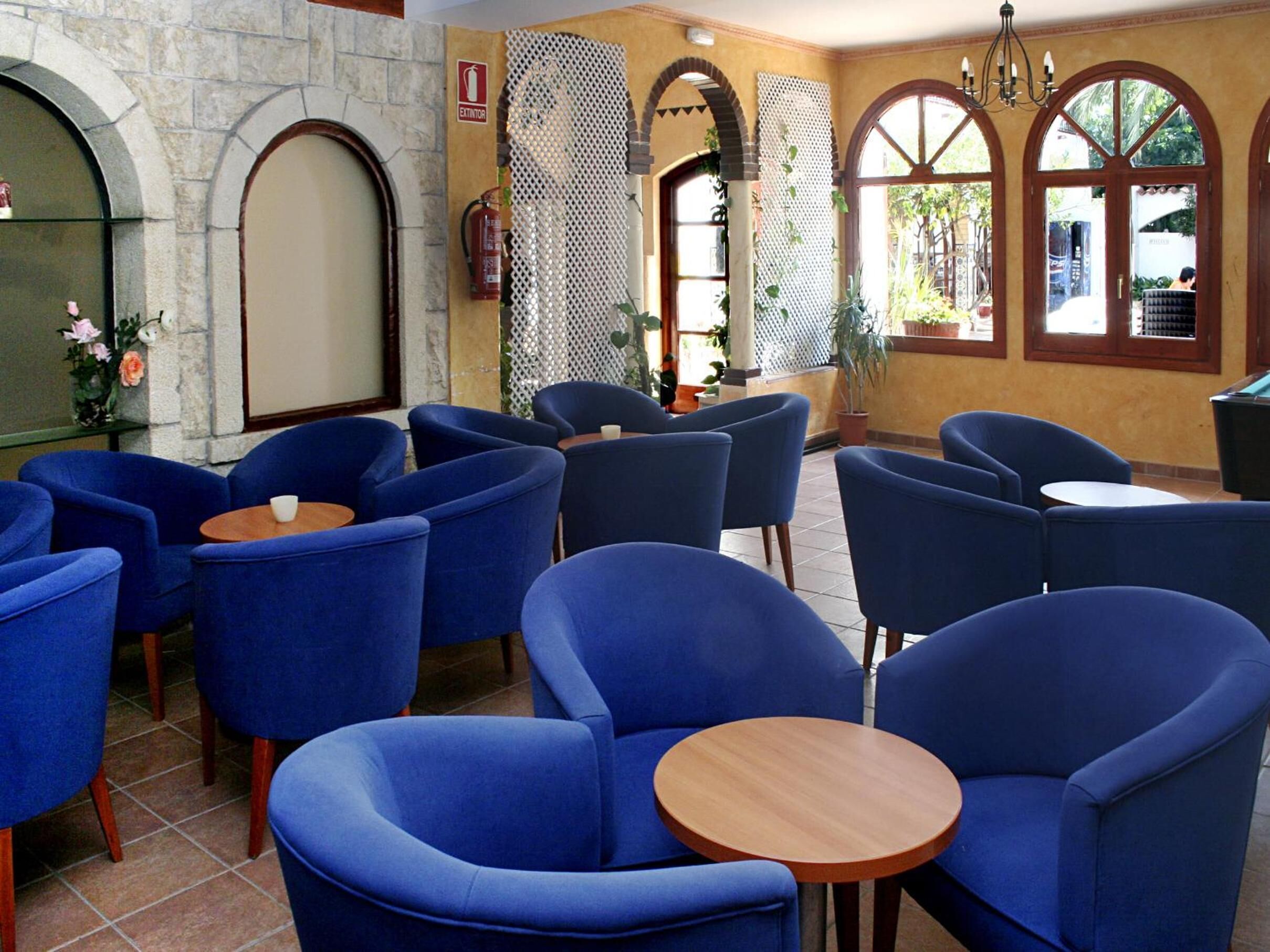 A restaurant with blue chairs and tables, stone walls, and arched windows.