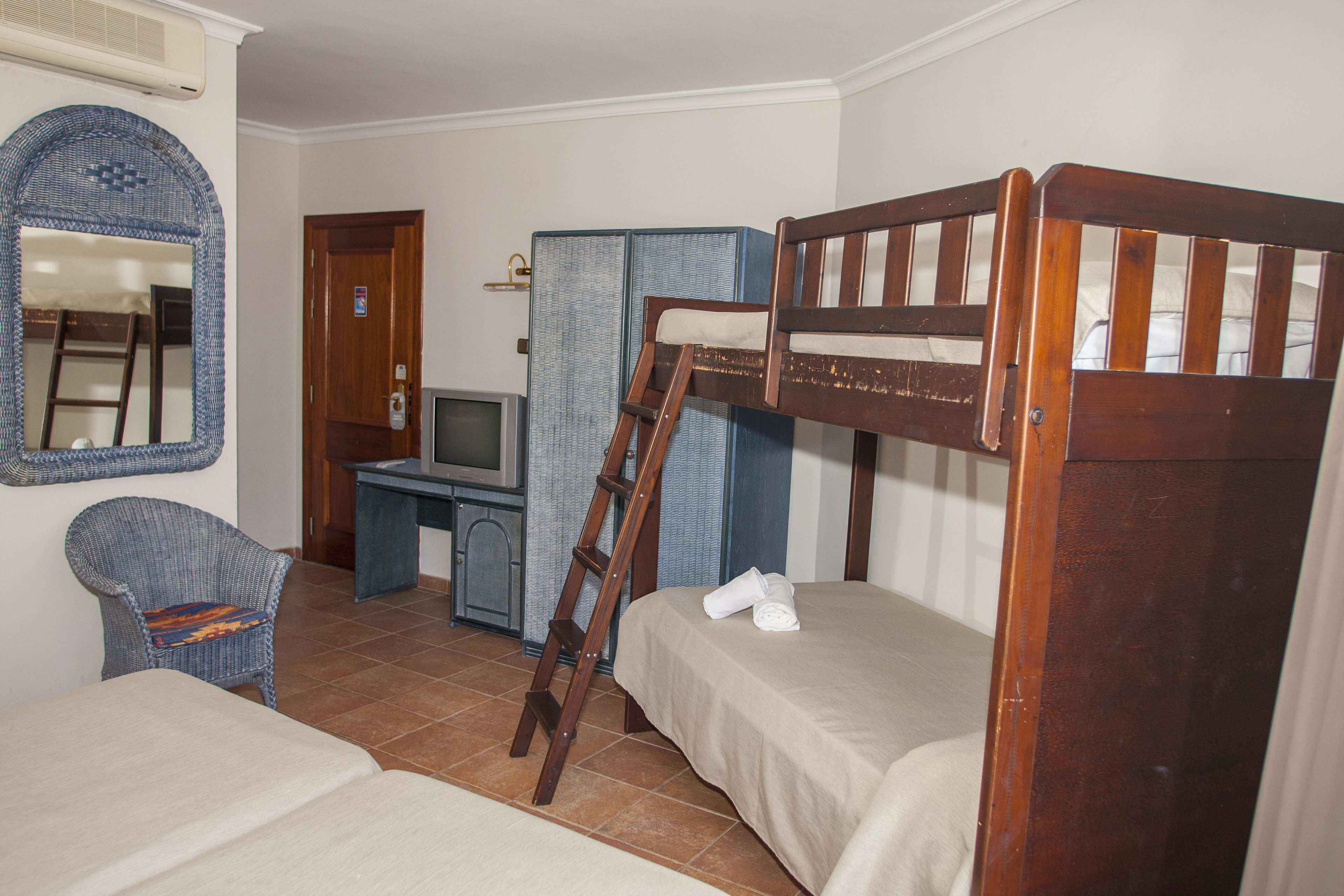 A room with two bunk beds, a desk with a computer, a chair, and a television.