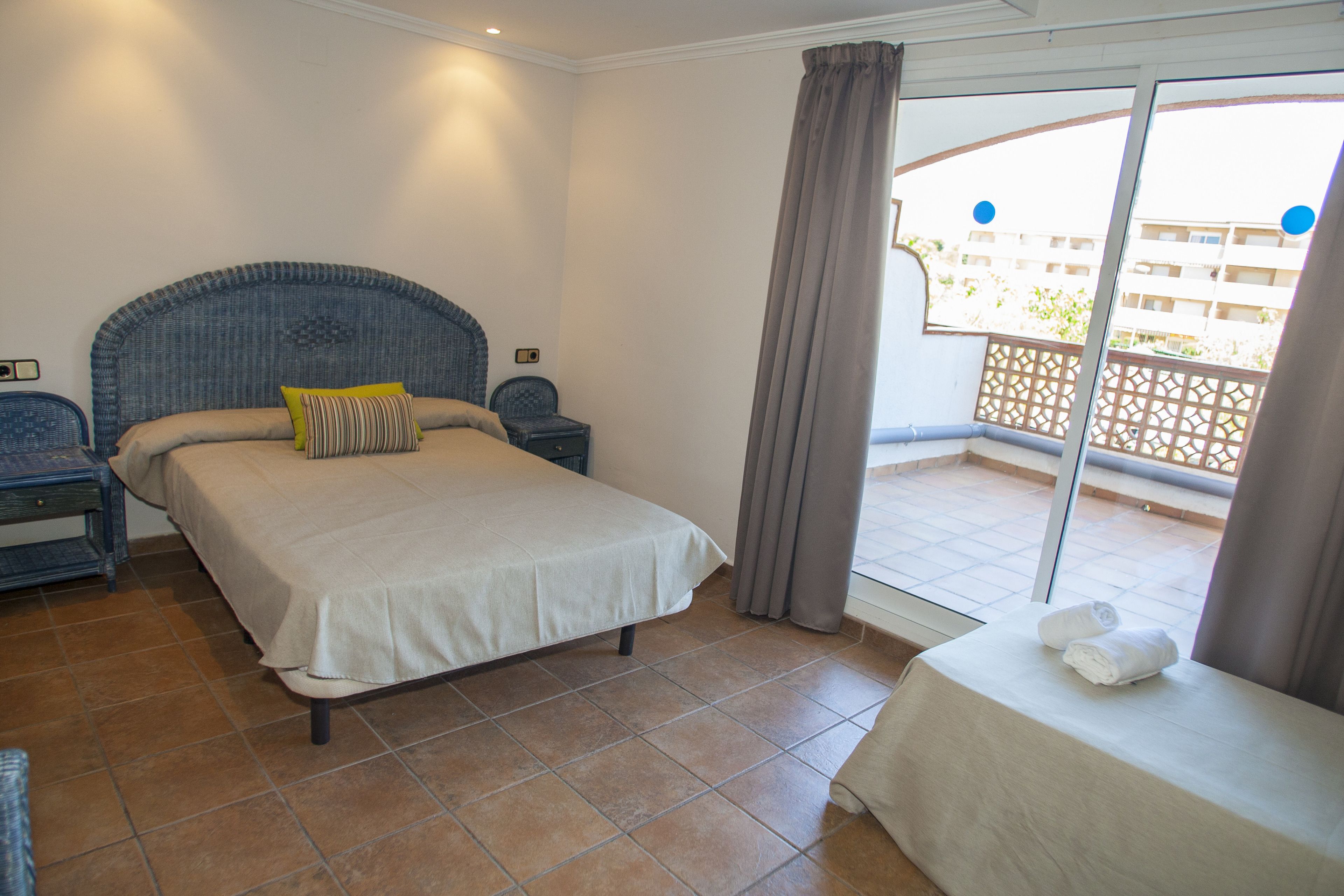Een slaapkamer met een bed, nachtkastjes, een klein tafeltje met handdoeken en een balkon met uitzicht.