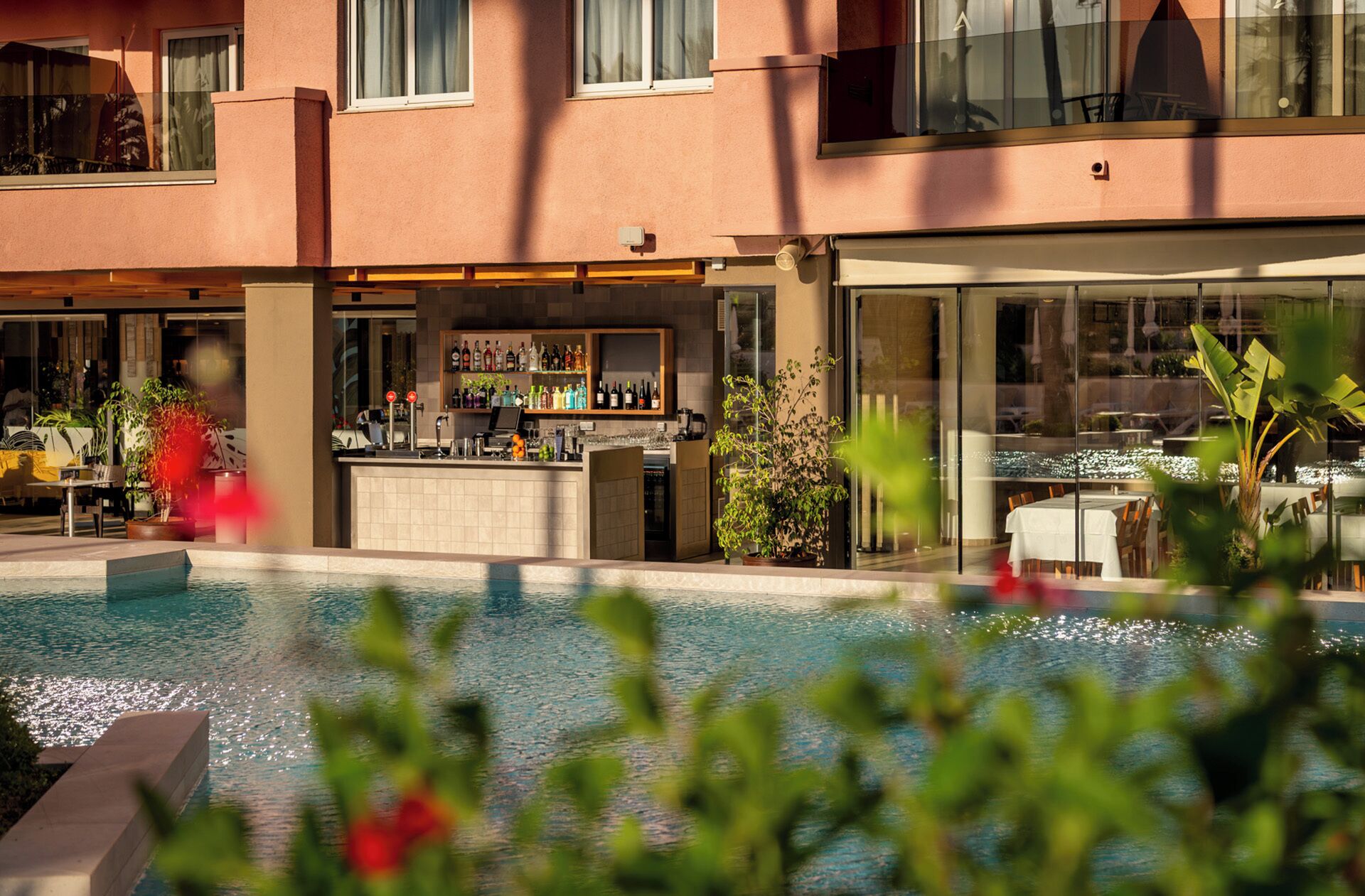 Ein Barbereich am Pool mit Bar, Sitzgelegenheiten und Blick auf den Pool.