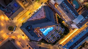 An aerial view of a hotel with a central courtyard, multiple floors, and a swimming pool.