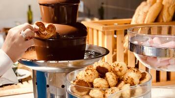 A buffet setup with various food items including pretzels, tater tots, and other snacks.