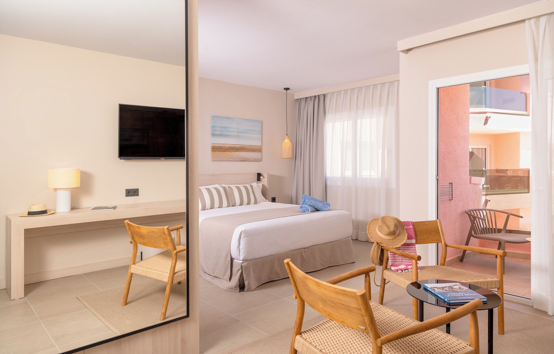 Habitación de hotel con cama, escritorio, silla, mesa pequeña, televisión y ventana con cortinas.