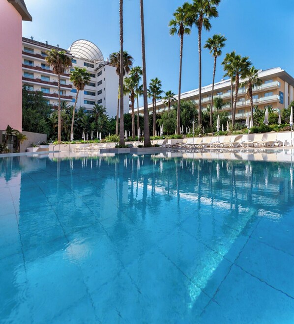 Alberca al aire libre, sombrillas en la alberca y camastros 