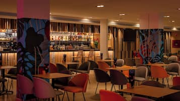 A modern bar area with a variety of seating options and a bar stocked with bottles.