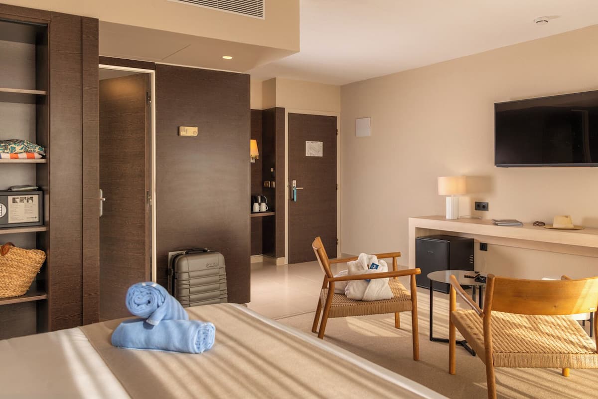 Una habitación de hotel con una cama, un escritorio, un televisor, una silla y una mesita.