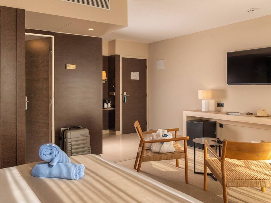 A hotel room with a bed, a desk, a television, a chair, and a small table.