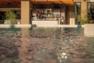 Una piscina al aire libre, sombrillas, sillones reclinables de piscina