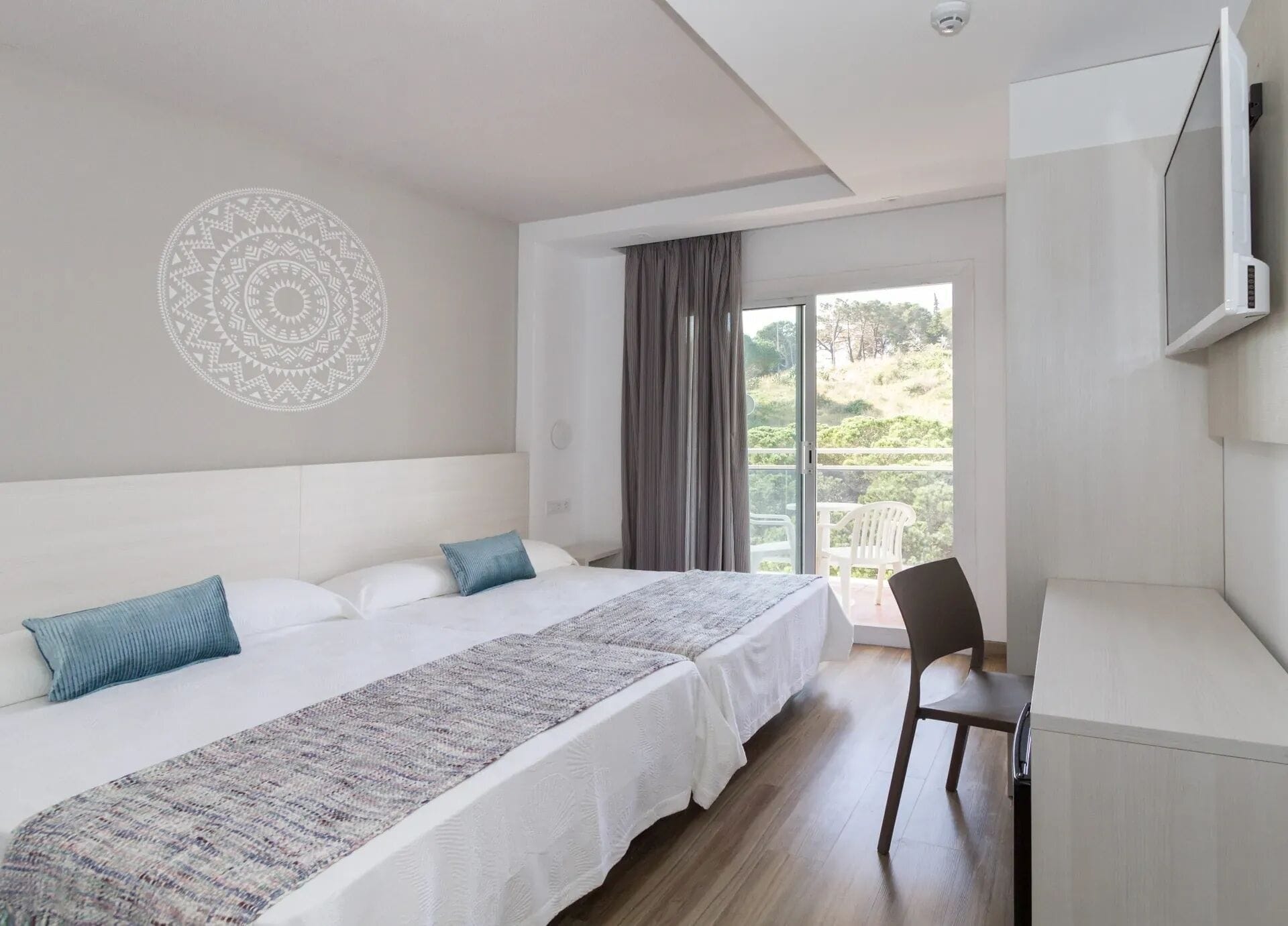 Ein Schlafzimmer mit Bett, Schreibtisch, Stuhl, einem großen Fenster und einer Wanddekoration.