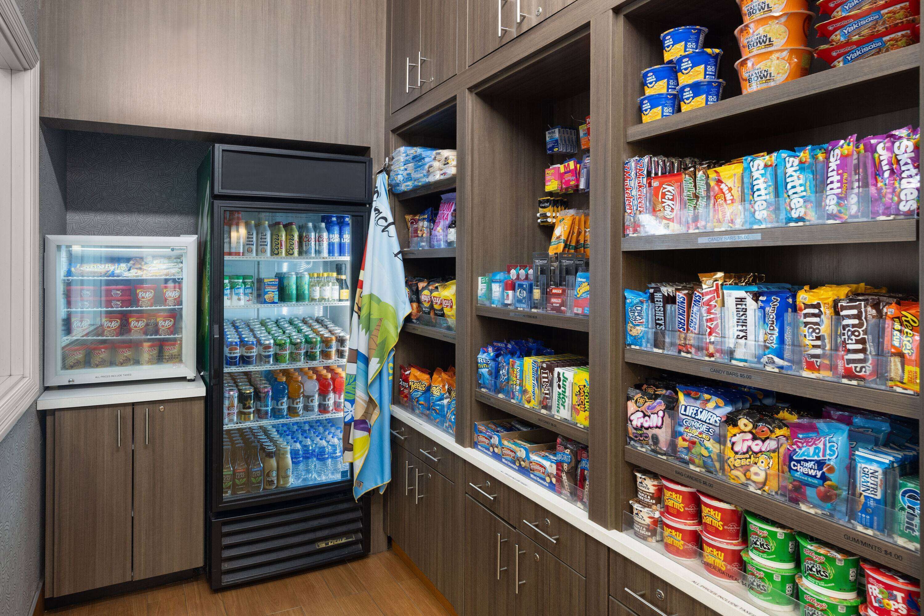 A snack and beverage section with a refrigerator, shelves stocked with snacks, and a variety of drinks.