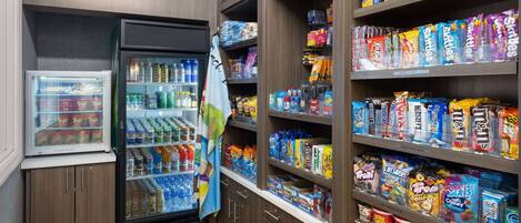 A snack and beverage section with a refrigerator, shelves stocked with snacks, and a variety of drinks.