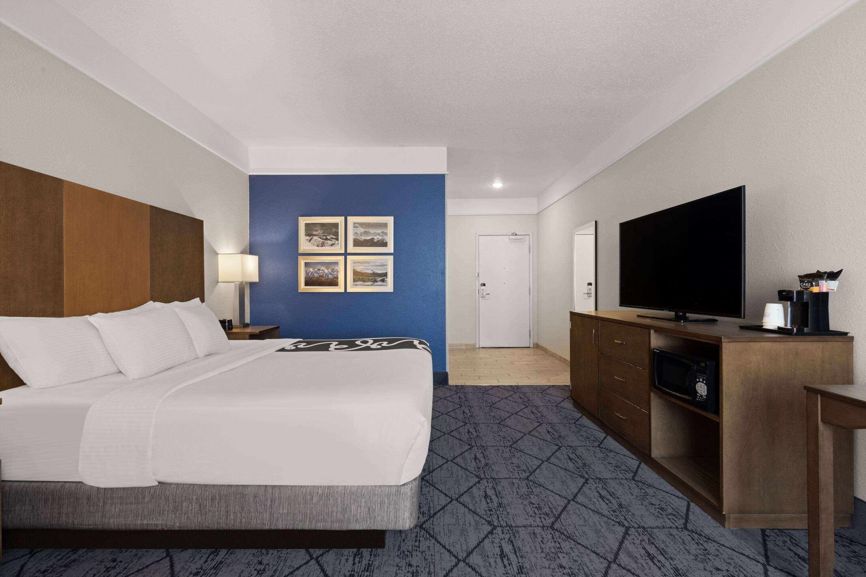 Een hotelkamer met een bed, een televisie, een bureau en een kast.
