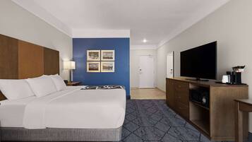 Een hotelkamer met een bed, een televisie, een bureau en een kast.