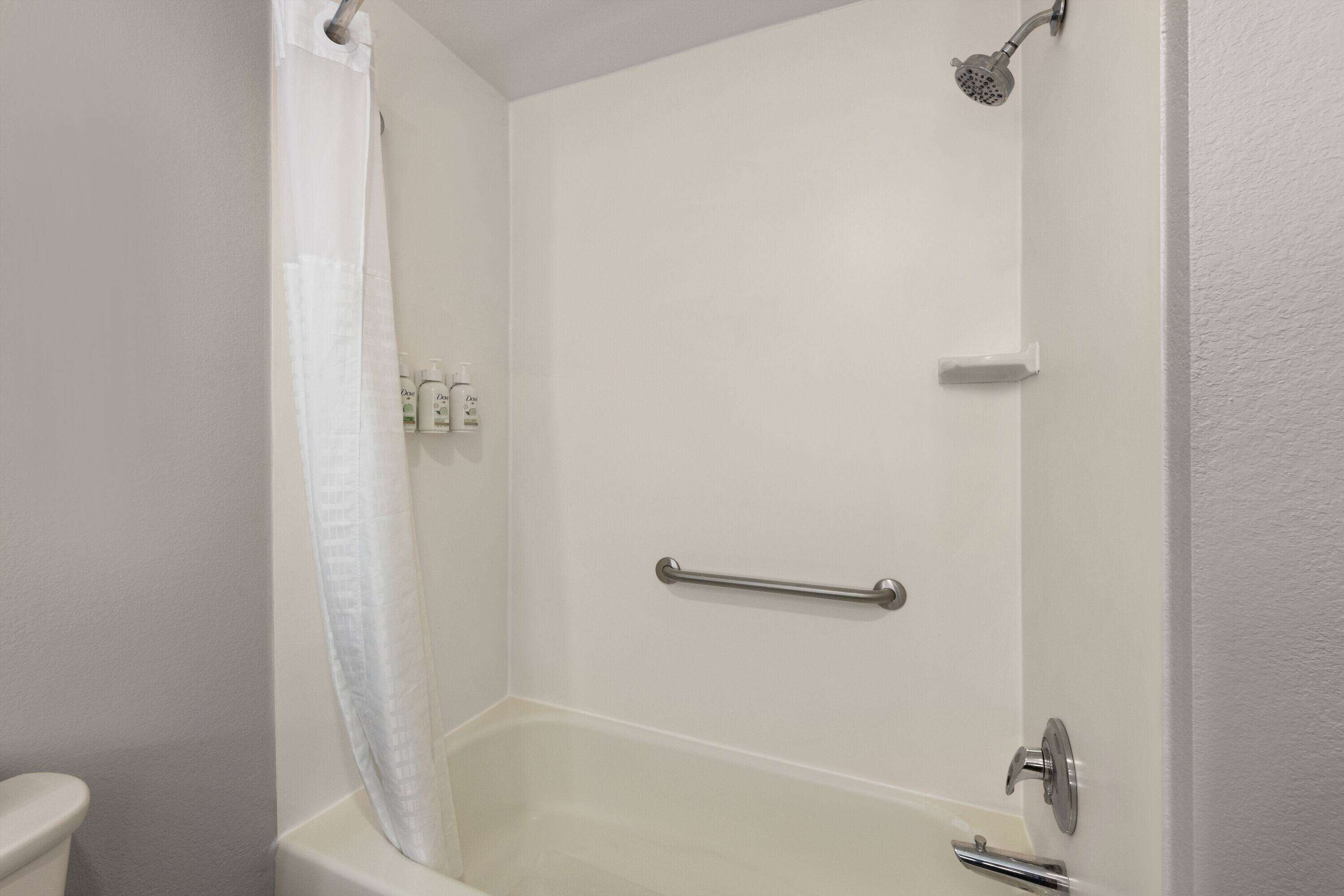 A bathroom with a bathtub, a shower, and a toilet. There are toiletries on the wall.