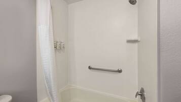 A bathroom with a bathtub, a shower, and a toilet. There are toiletries on the wall.