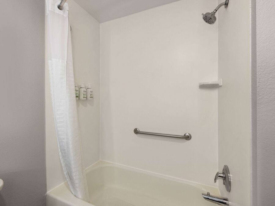 A bathroom with a bathtub, a shower, and a toilet. There are toiletries on the wall.