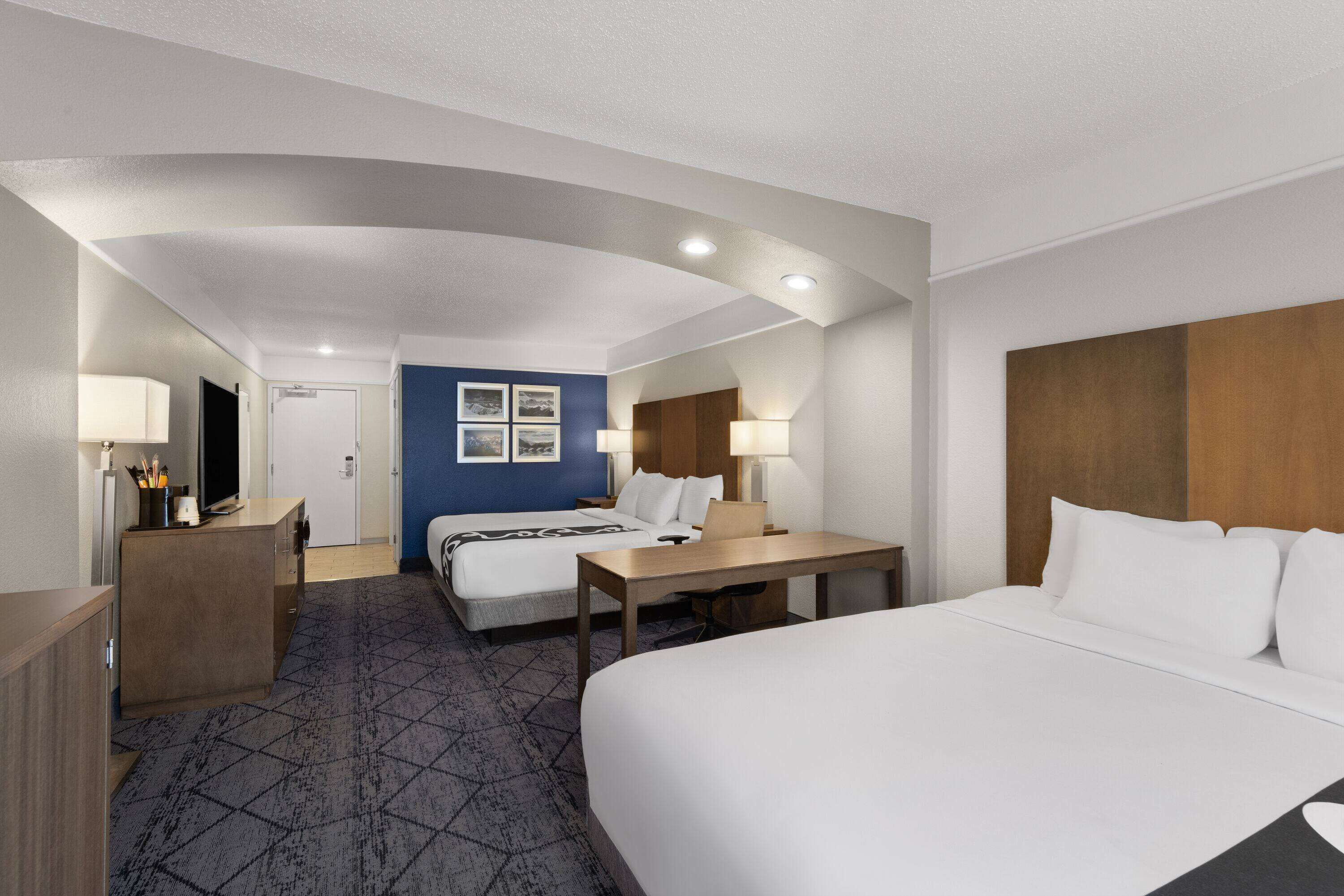 Een hotelkamer met een groot bed, een bureau, een stoel, een televisie en een kledingkast.