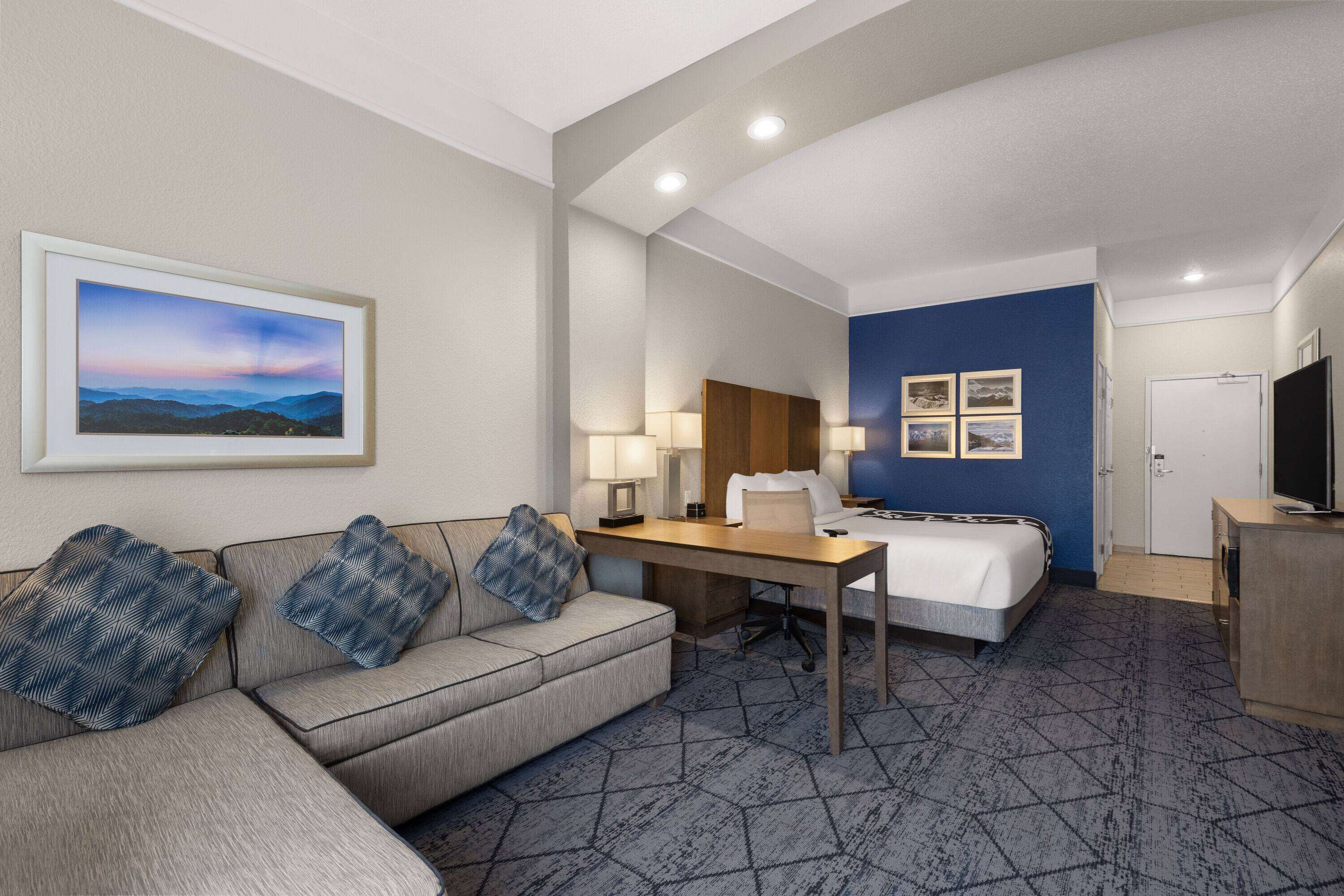 Une chambre d’hôtel avec un lit, un bureau, un canapé et une télévision.