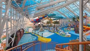 Un parque acuático interior con toboganes, piscinas y zonas de estar.