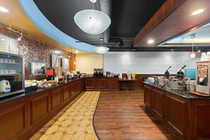 A modern kitchen with wooden cabinets, a central island, and a patterned floor. - La Quinta Inn and Suites by Wyndham at WaTiki Waterpark (Rapid City)