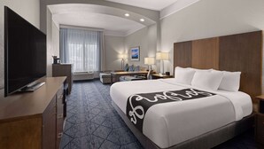 Habitación de hotel con una cama grande, televisión de pantalla plana, escritorio con silla y ventana con cortinas.