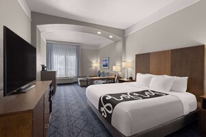 Habitación de hotel con una cama grande, televisión de pantalla plana, escritorio con silla y ventana con cortinas.