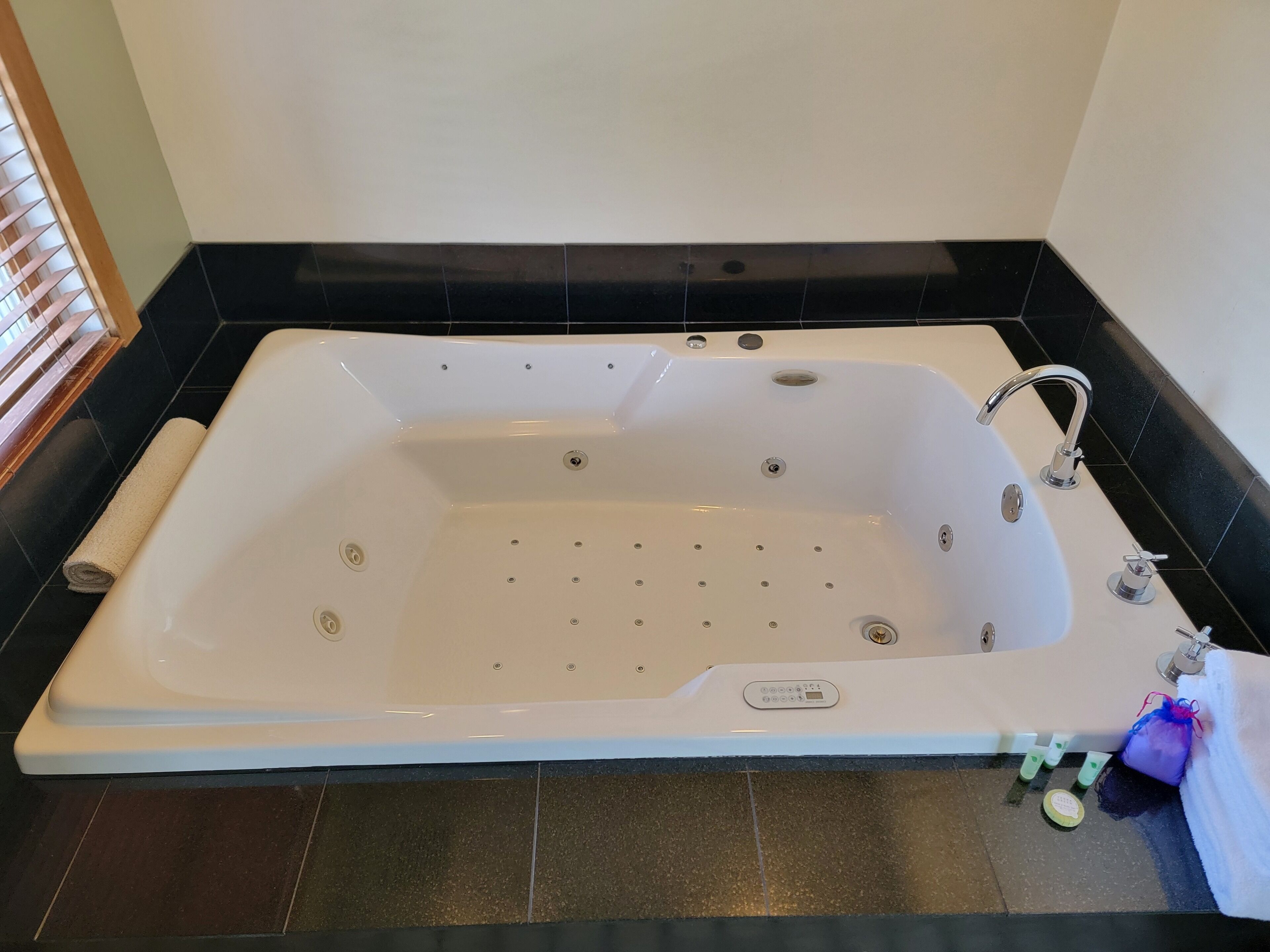 A large, white bathtub with a control panel, surrounded by black tiles.