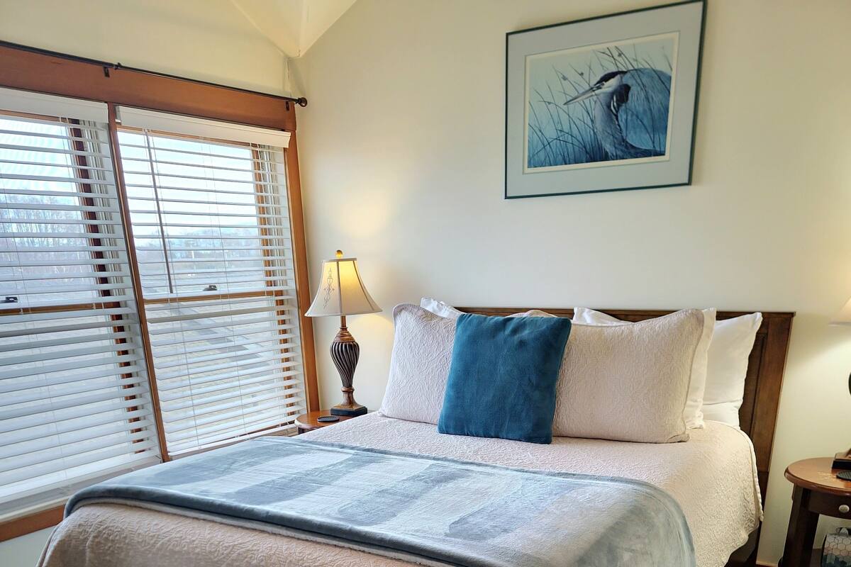 A neatly made bed with a patterned bedspread, a blue pillow, and a headboard.