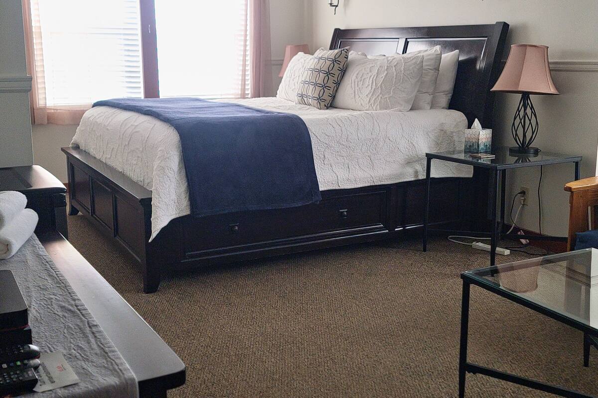 A neatly arranged bedroom with a bed, bedside tables, a desk, and a lamp.
