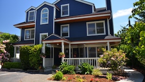 A two-story house with a porch, a chimney, and a well-maintained garden. - The Heron Inn & Day Spa (La Conner)