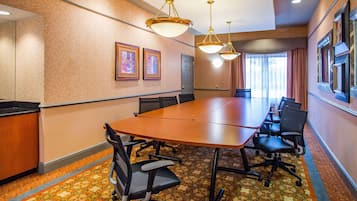 A conference room with a long table, chairs, and framed artwork on the walls.