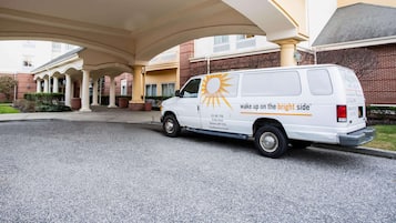 A white van parked under a covered area with a sun logo and text.