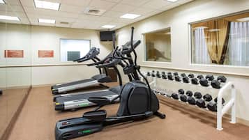 A gym with treadmills, elliptical machines, and a rack of dumbbells.