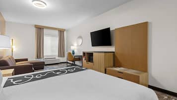 Una camera d'albergo con un letto, una scrivania, una sedia, una televisione e una finestra con tende.